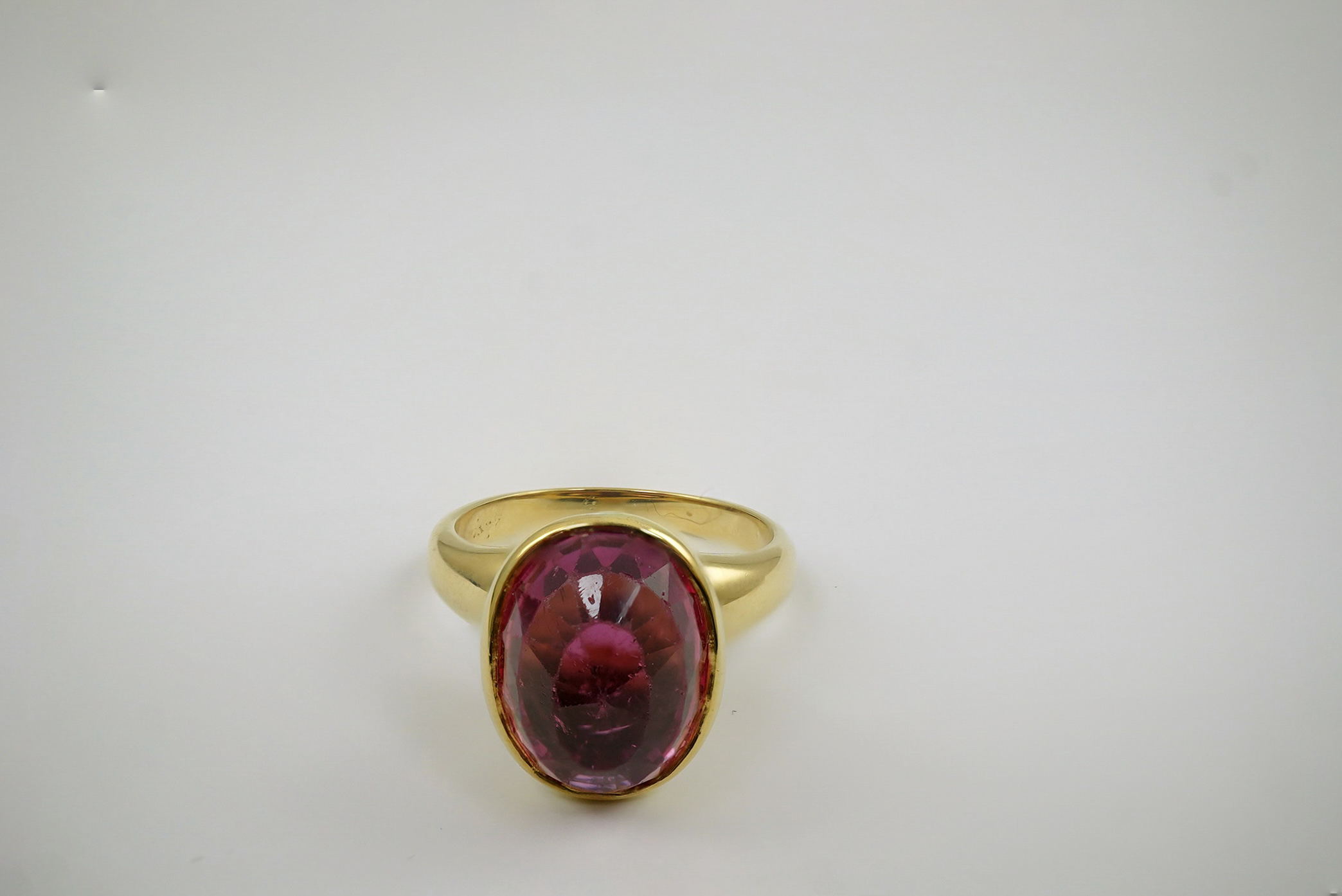 A modern 18k gold and single stone fancy oval cut deep pink tourmaline set dress ring, signed Asprey?